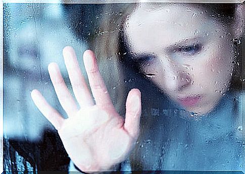 Sad woman looking out the window because of an emotional predator