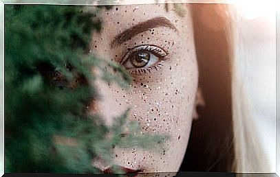 Woman behind tree branch representing that happiness is not the absence of problems