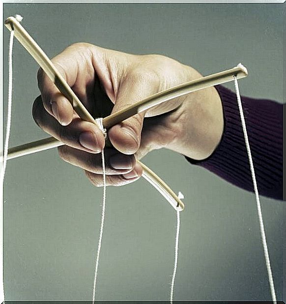 Hand manipulating the strings of a puppet to represent a manipulator