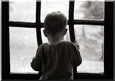 Sad and lonely child looking out the window feeling the weight of an open wound