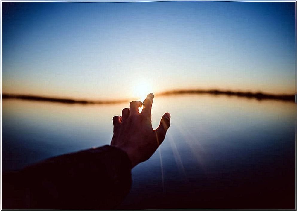 Hand touching a sun at sunset